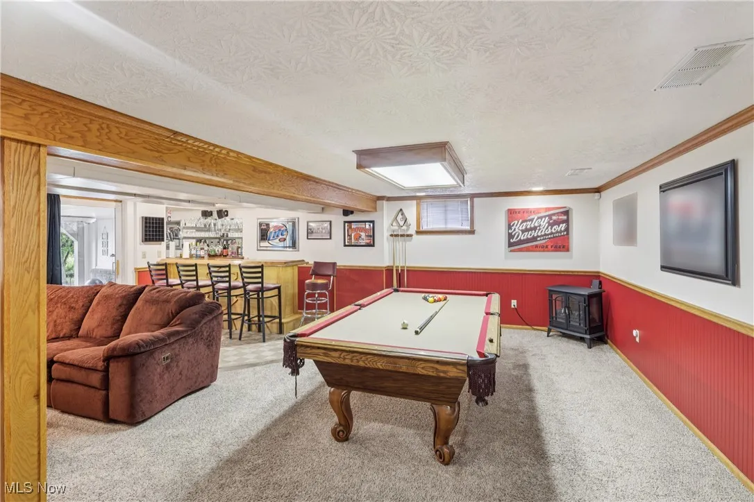 Lower level recreation room with a bar, slider to heated 4 season / sun room and carpet floorng