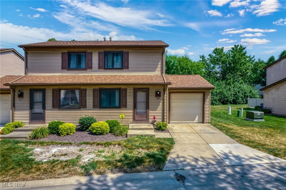 View of front of property with a garage, driveway, a front yard, and roof with shingles
