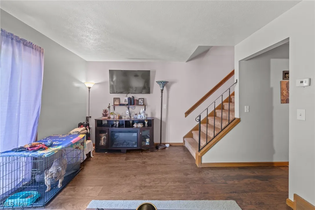 Living area with wood finished floors, stairs, and a textured ceiling
