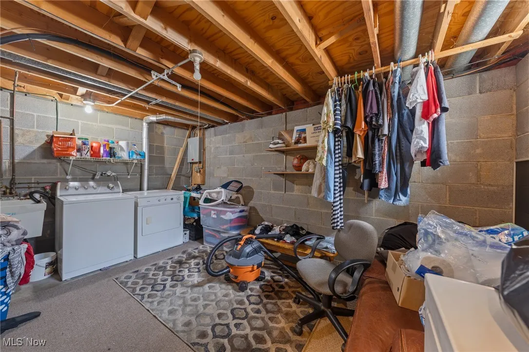Unfinished below grade area with separate washer and dryer and concrete block wall