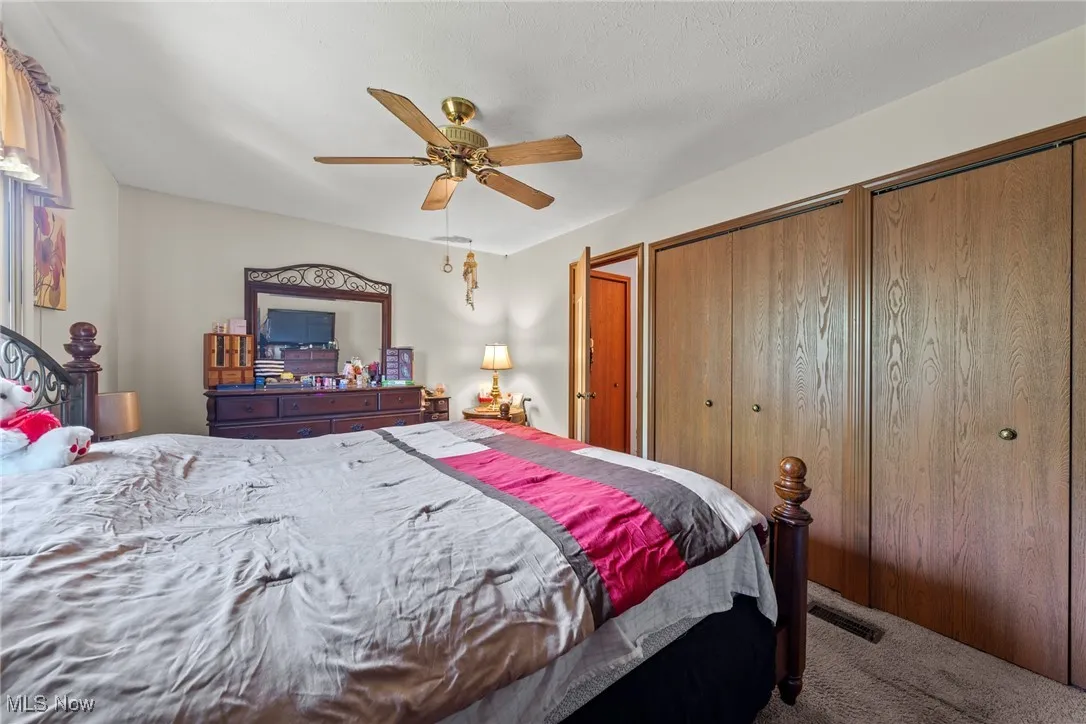 Carpeted bedroom with two closets and ceiling fan