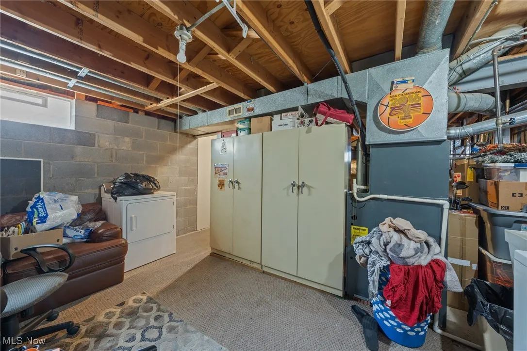 Below grade area featuring washer / dryer, carpet floors, heating unit, and concrete block wall