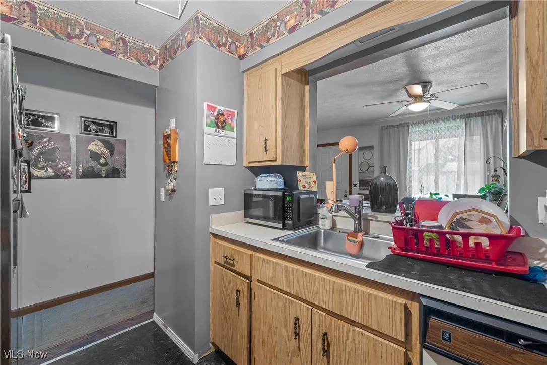 Kitchen with dishwasher, stainless steel microwave, ceiling fan, and light countertops
