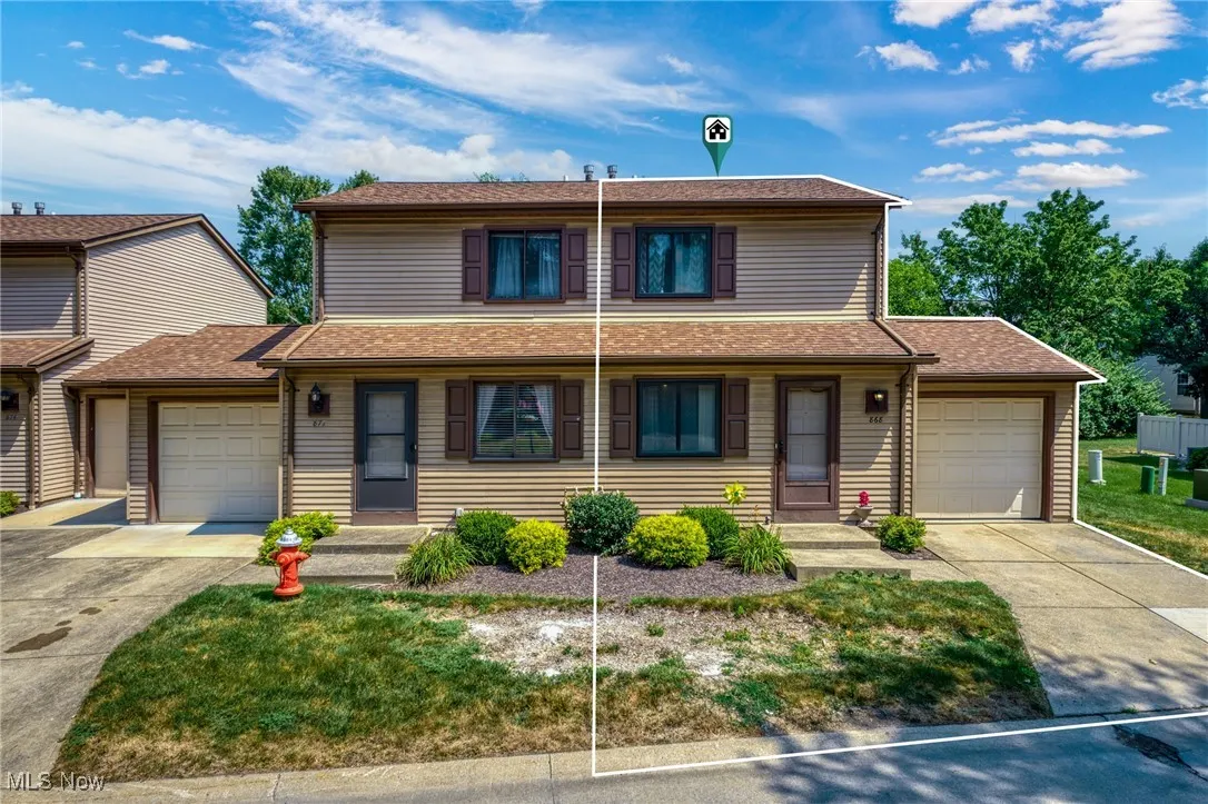 Traditional home featuring a garage, concrete driveway, and a shingled roof