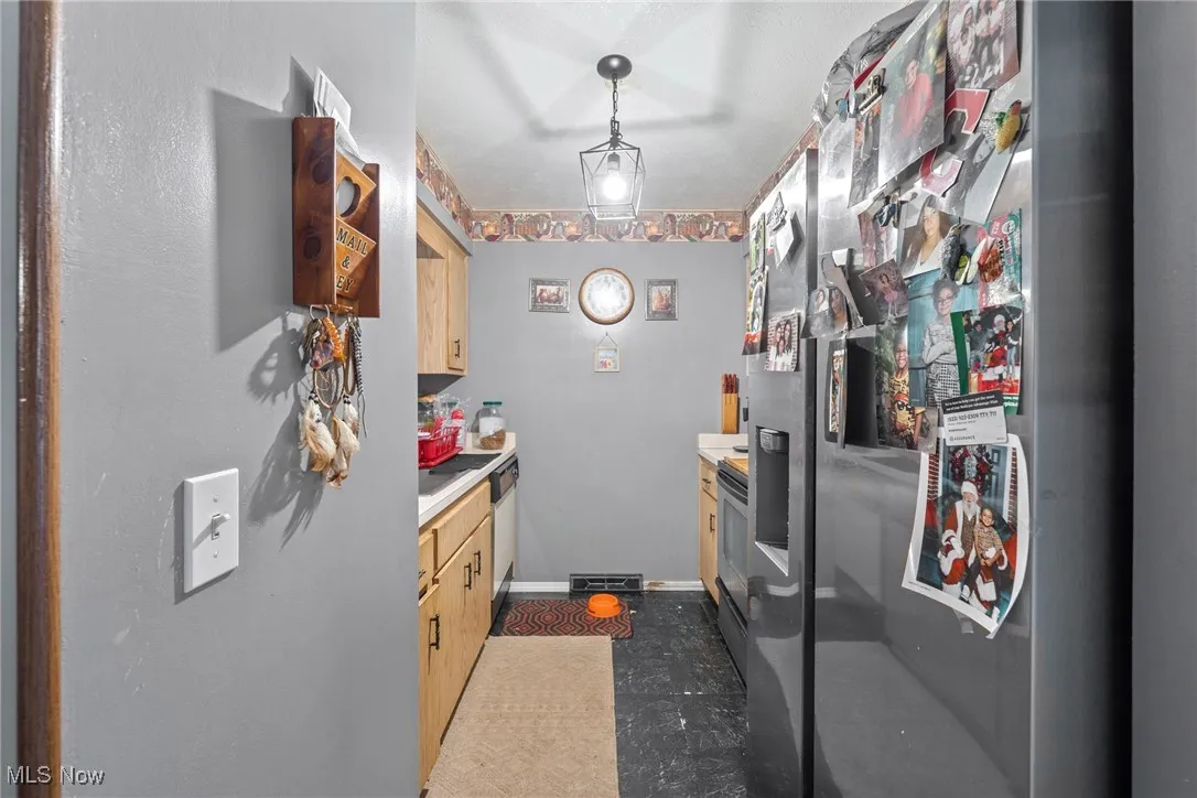 Kitchen with appliances with stainless steel finishes, light countertops, and light brown cabinetry