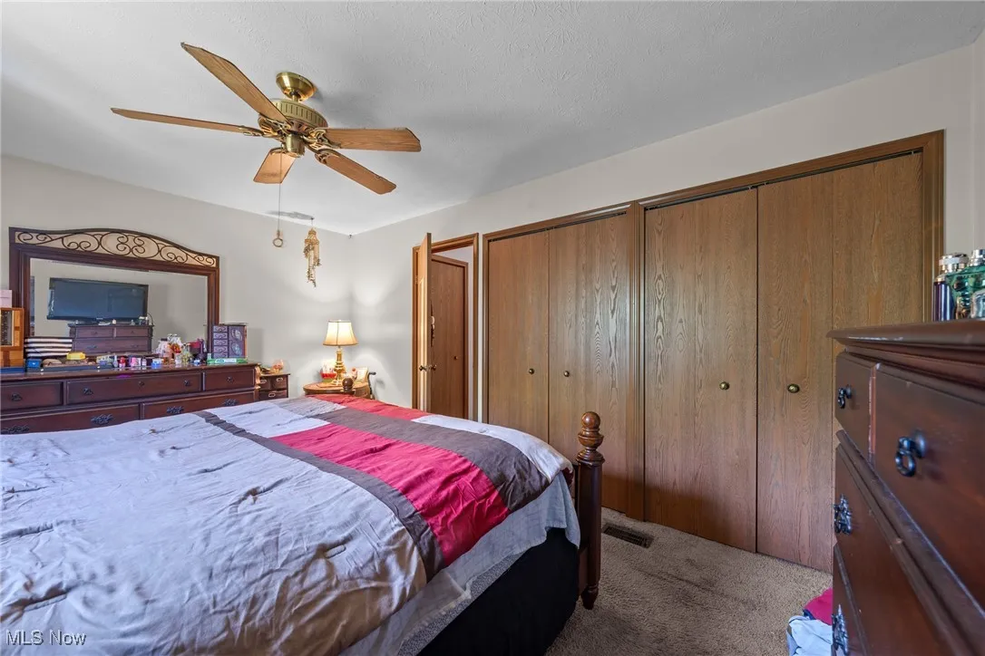 Bedroom featuring carpet, two closets, and a ceiling fan
