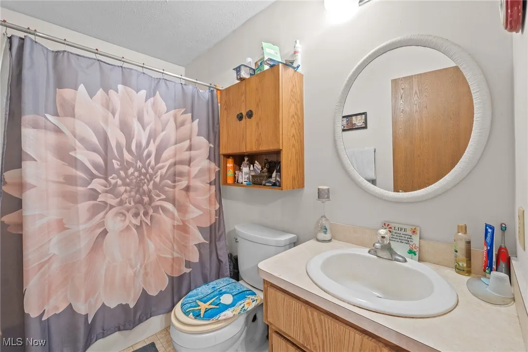 Bathroom with vanity, a shower with curtain, and a textured ceiling