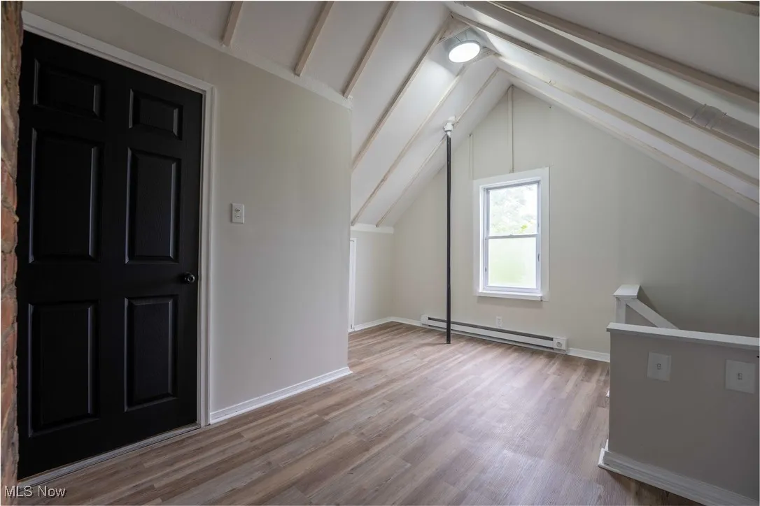 Bonus room with a baseboard radiator, lofted ceiling, and light wood finished floors