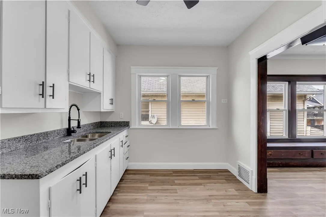 Kitchen featuring light wood finished floors, white cabinetry, and dark stone countertops