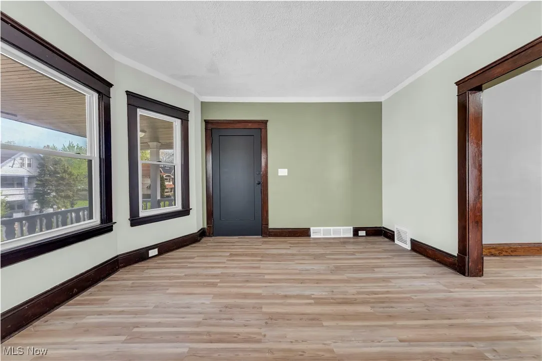 Spare room featuring light wood-style floors, a textured ceiling, and crown molding
