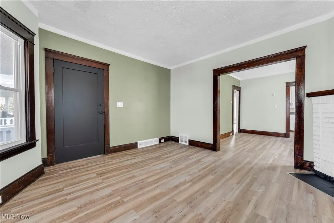 Spare room with light wood finished floors, crown molding, and a textured ceiling