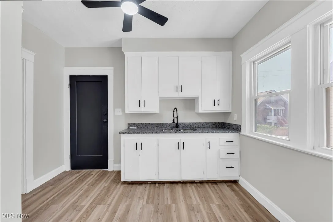 Kitchen featuring dark countertops, light wood finished floors, white cabinets, and a ceiling fan