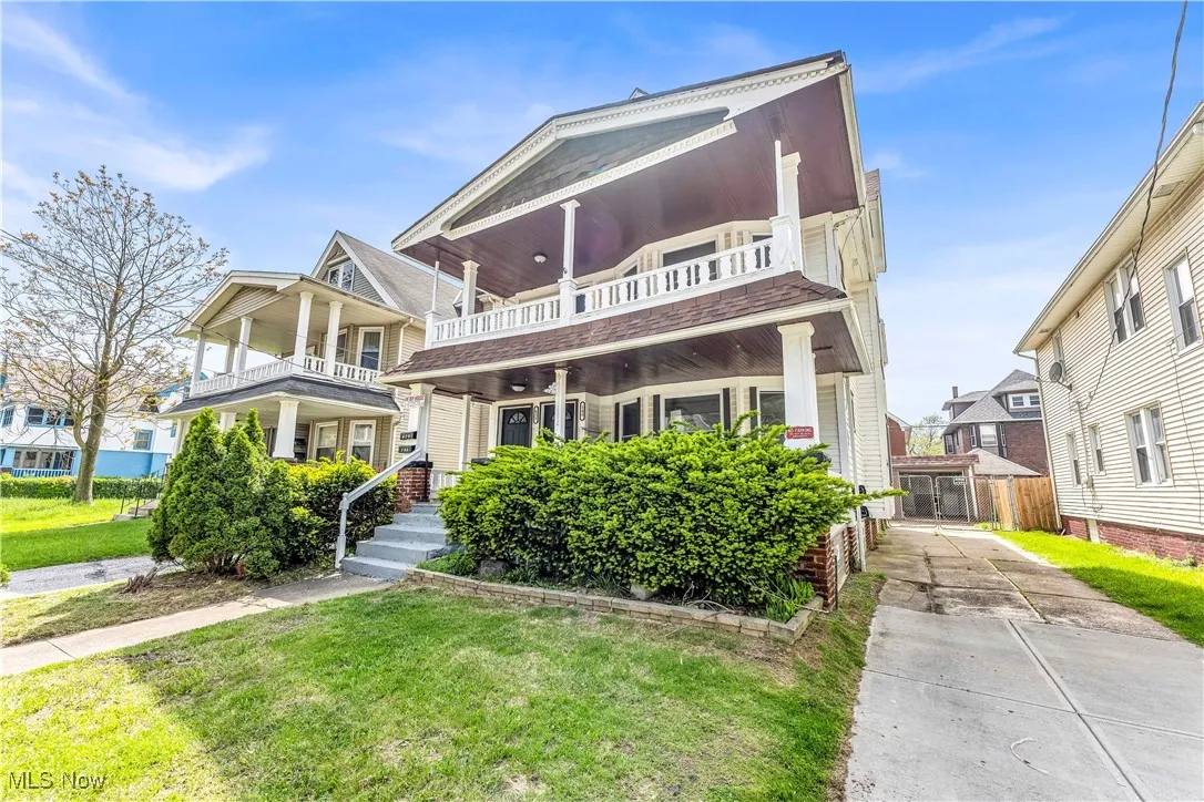 View of front facade with a balcony, a front yard, and driveway