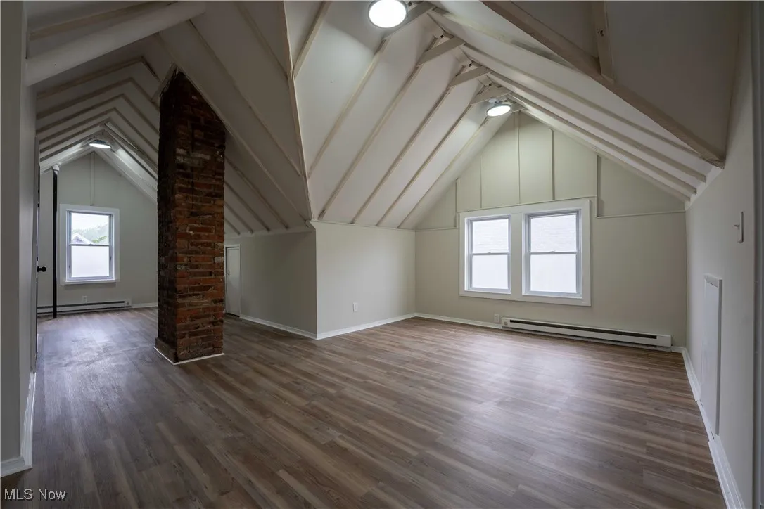 Bonus room featuring a baseboard radiator, wood finished floors, and ornate columns