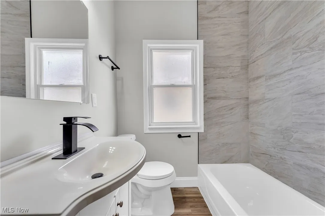 Bathroom with vanity, a bath, and wood finished floors