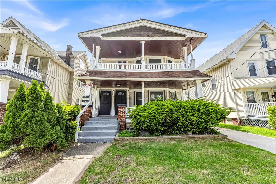 View of front facade with a balcony, covered porch, and a front yard