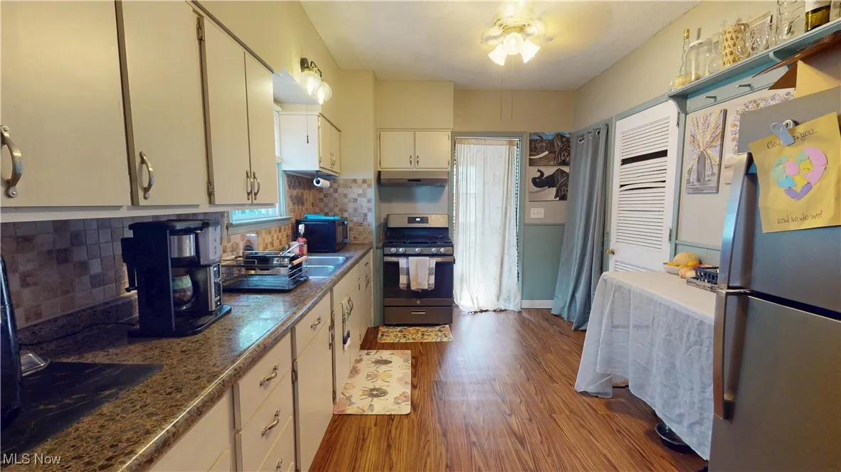 Kitchen featuring stainless steel appliances, dark wood-style flooring, tasteful backsplash, and ceiling fan
