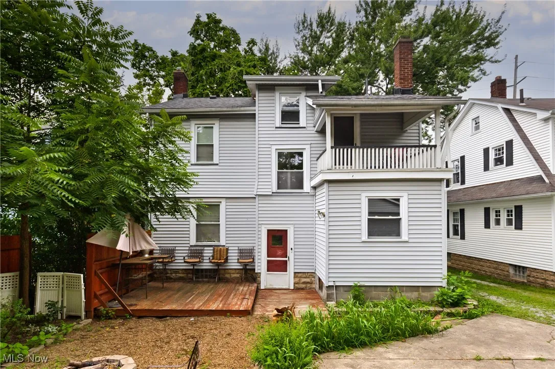 Back of house with a chimney, a wooden deck, and a balcony
