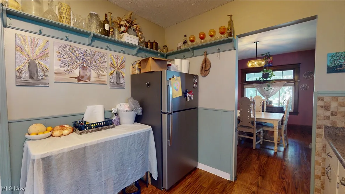 Kitchen with dark wood-type flooring and freestanding refrigerator