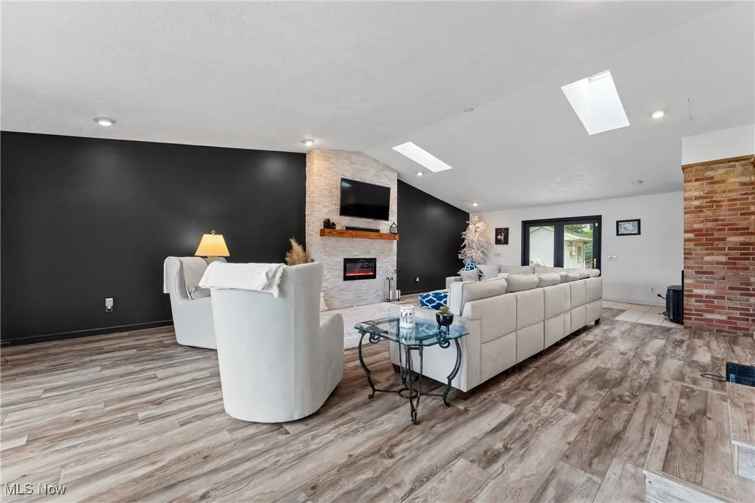 Living area featuring a skylight, a fireplace, wood finished floors, and vaulted ceiling