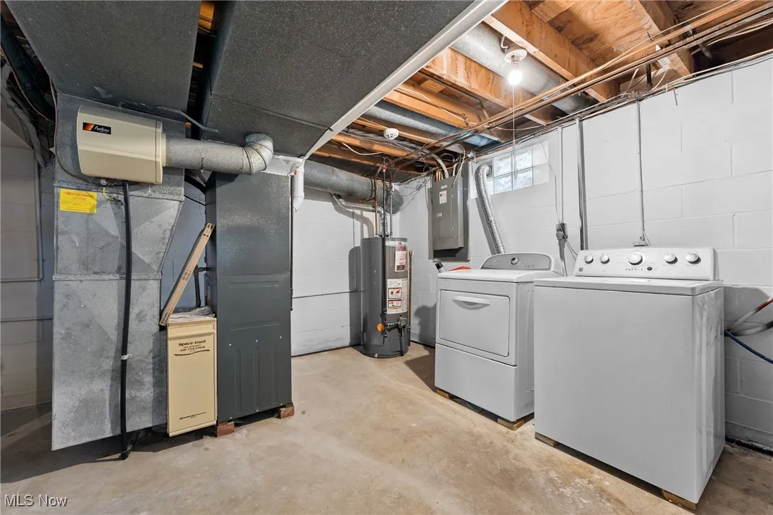 Basement with washer and clothes dryer, gas water heater, electric panel, and concrete block wall