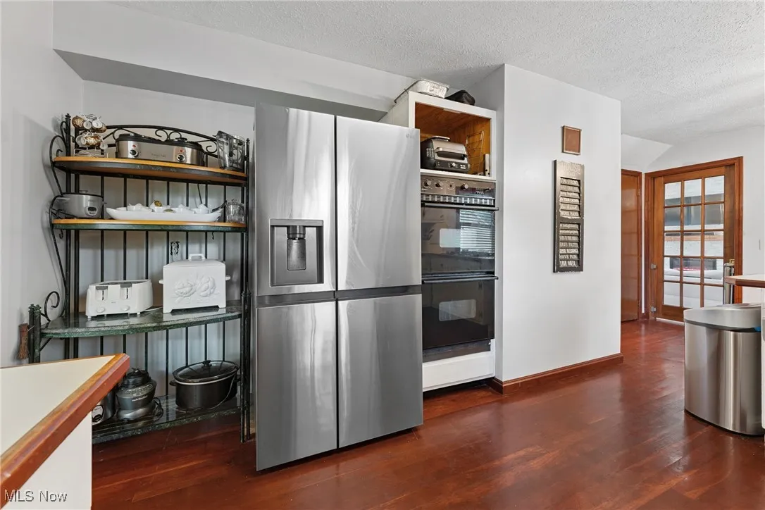 Kitchen featuring stainless steel fridge with ice dispenser, wood finished floors, and a textured ceiling