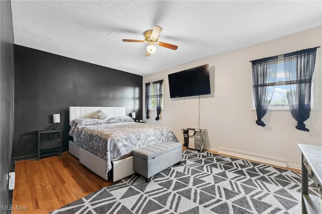 Bedroom featuring baseboard heating, wood finished floors, and ceiling fan