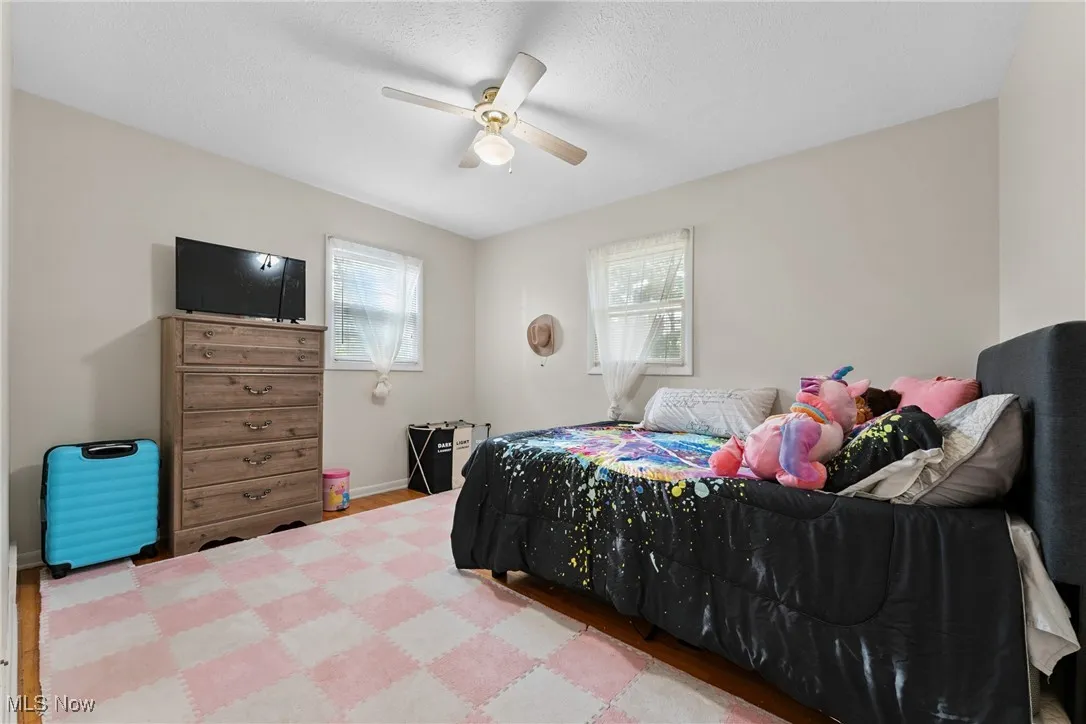 Bedroom with multiple windows, wood finished floors, and a ceiling fan