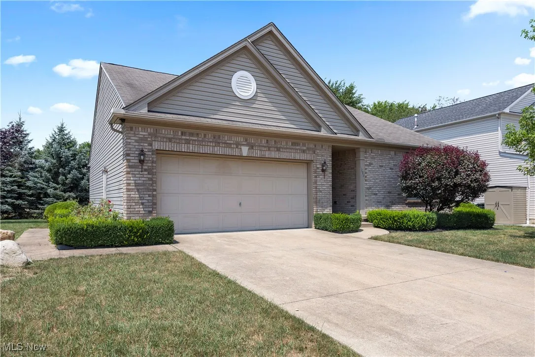 Single story home featuring brick siding, a garage, concrete driveway, and roof with shingles