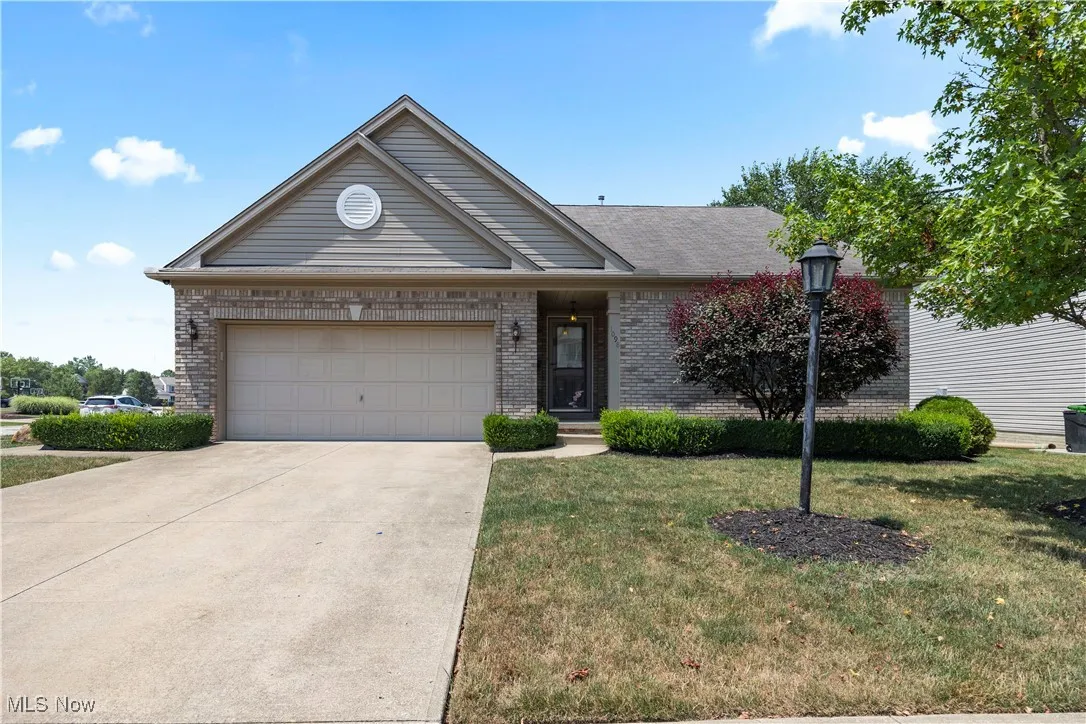 Single story home featuring driveway, a front lawn, a garage, and brick siding