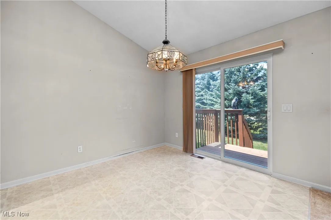 Unfurnished room featuring a chandelier and vaulted ceiling