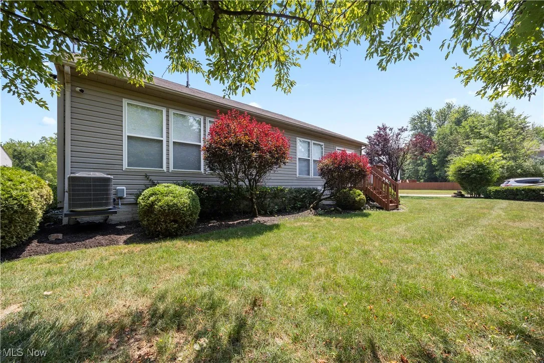 View of property exterior with a yard and stairway