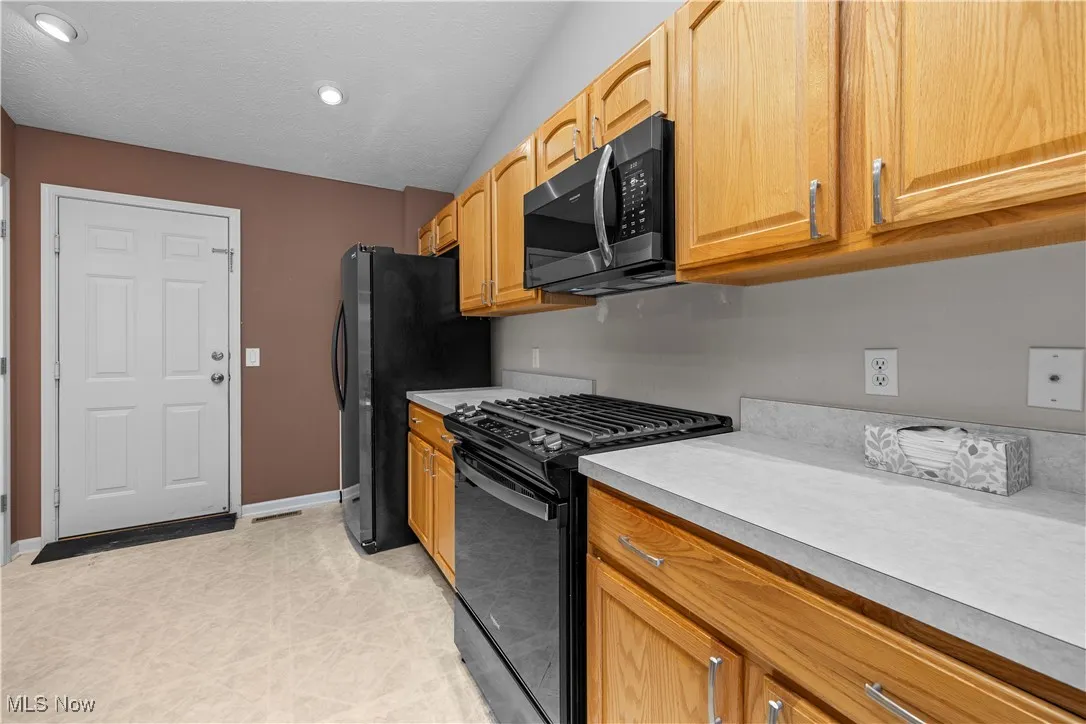 Kitchen featuring gas stove, stainless steel microwave, light countertops, and recessed lighting
