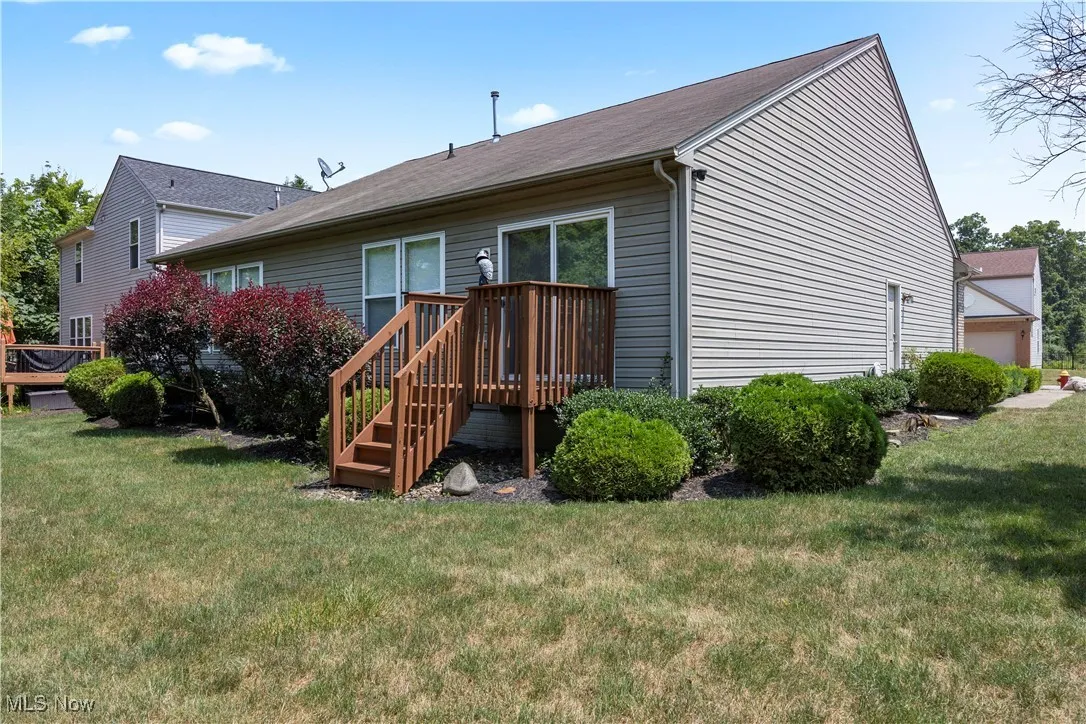 Rear view of house featuring a deck and a lawn