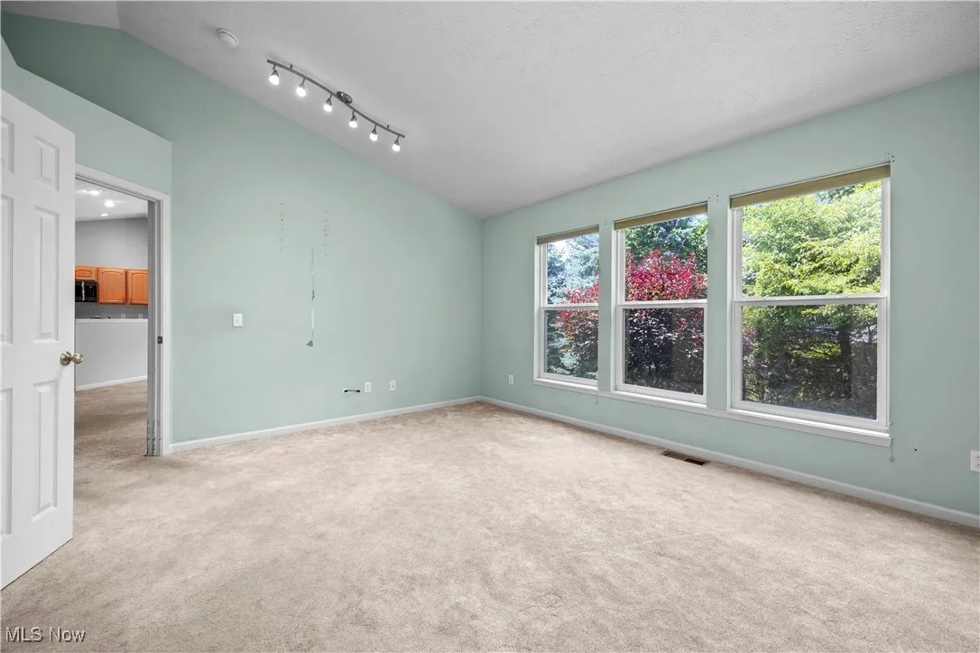 Carpeted empty room featuring lofted ceiling and baseboards
