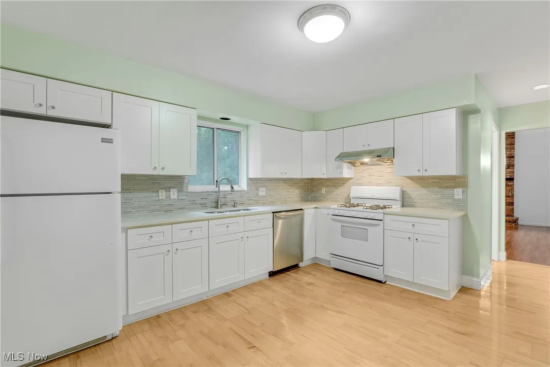 Updated kitchen with newer cabinetry, quartz countertops, newer appliances, wood flooring, and an inviting eat-in area