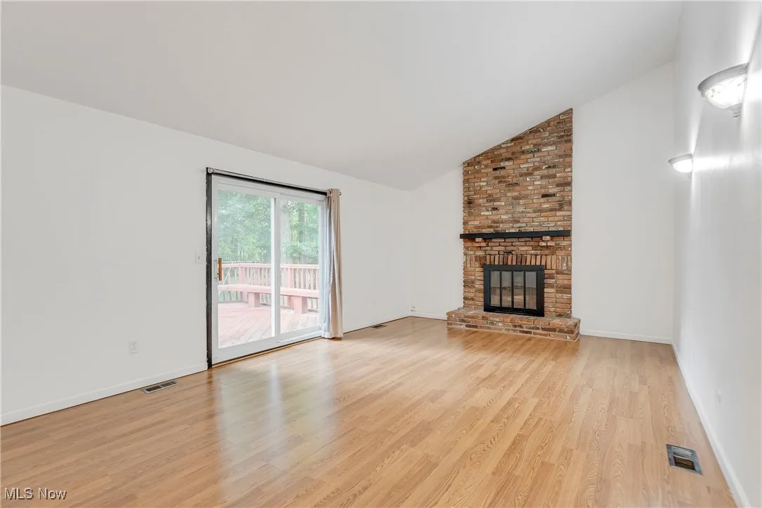 Family room features a vaulted ceiling, cozy fireplace and sliding doors that lead to a large deck and private, tree-lined backyard