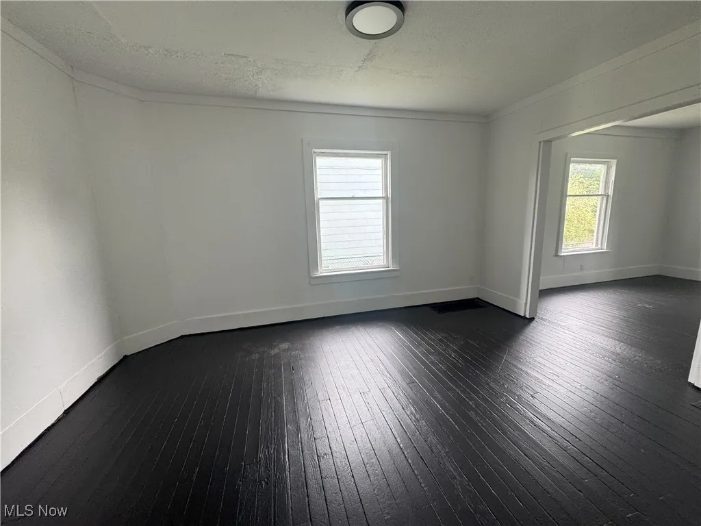 Empty room featuring dark wood finished floors and baseboards