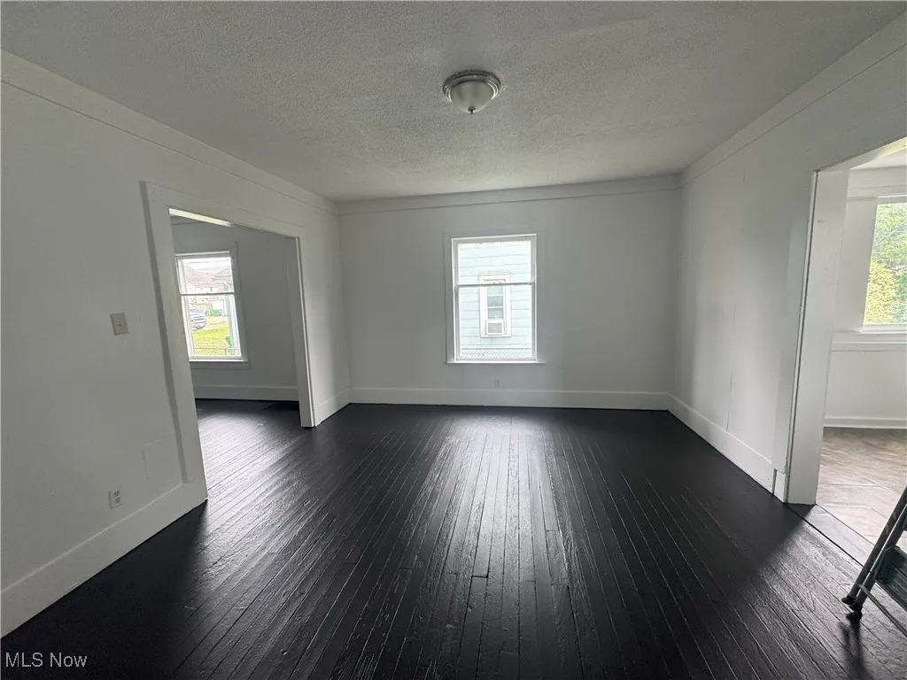 Empty room featuring dark wood-type flooring and a textured ceiling