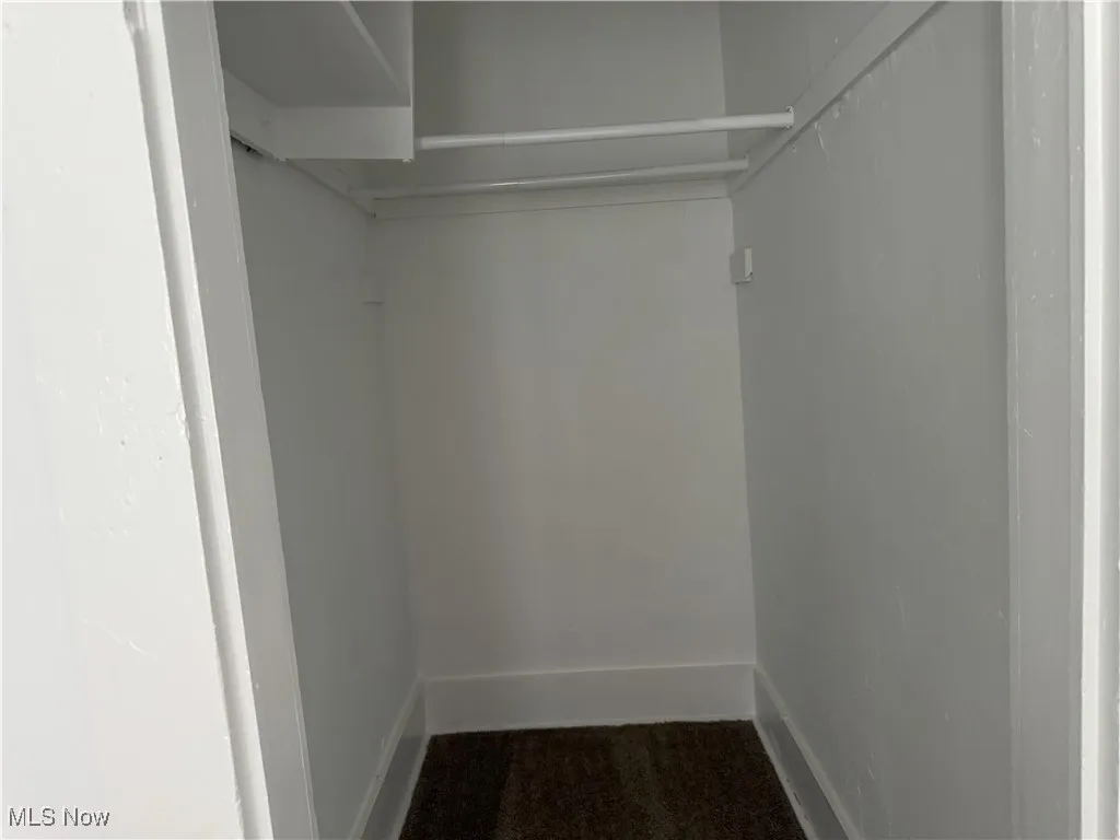 Walk in closet featuring dark colored carpet