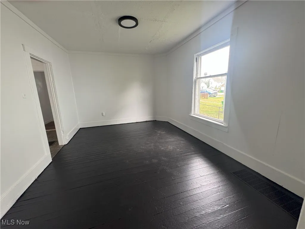 Empty room with dark wood finished floors and crown molding