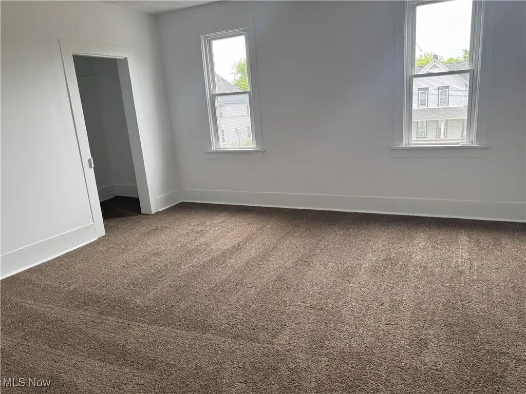 Empty room featuring dark carpet and baseboards