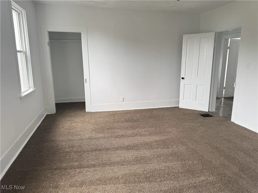 Unfurnished bedroom with carpet flooring and multiple windows
