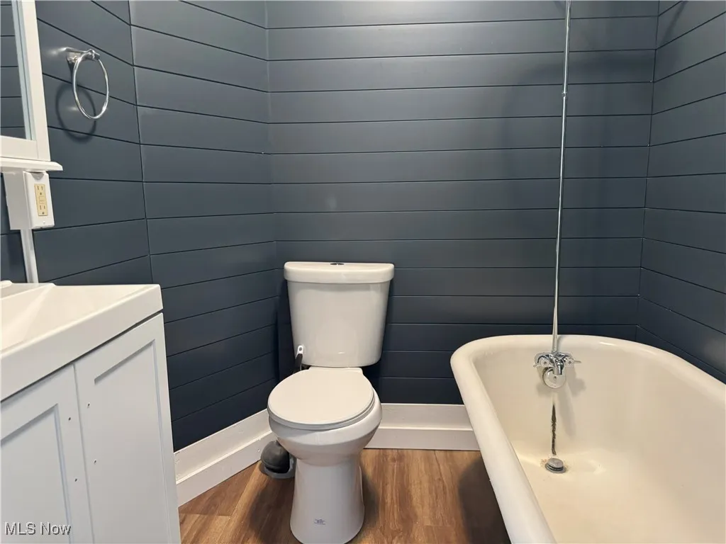 Full bathroom featuring wood finished floors, a soaking tub, and vanity