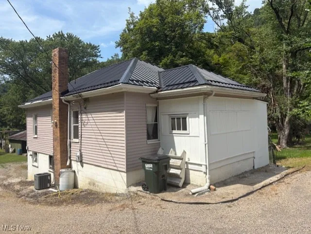 View of side of property with a chimney and a metal roof