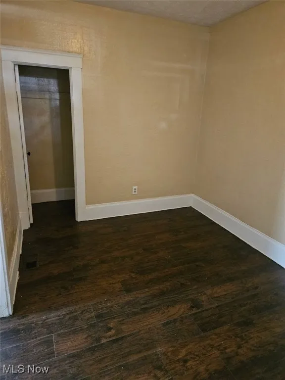 Unfurnished room with dark wood finished floors and baseboards