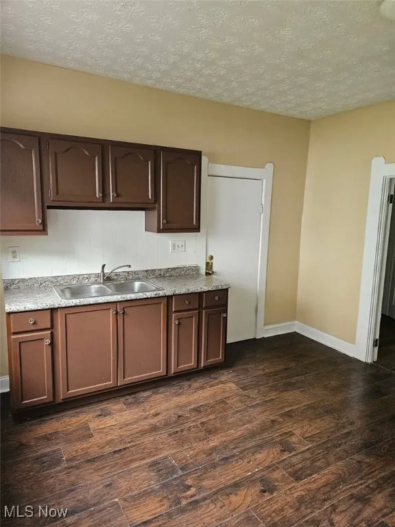 Kitchen featuring dark wood-style floors, a textured ceiling, light countertops, and dark brown cabinets