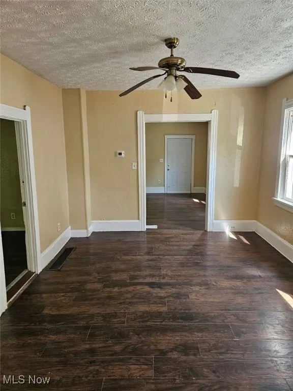 Spare room with wood finished floors, a textured ceiling, and ceiling fan