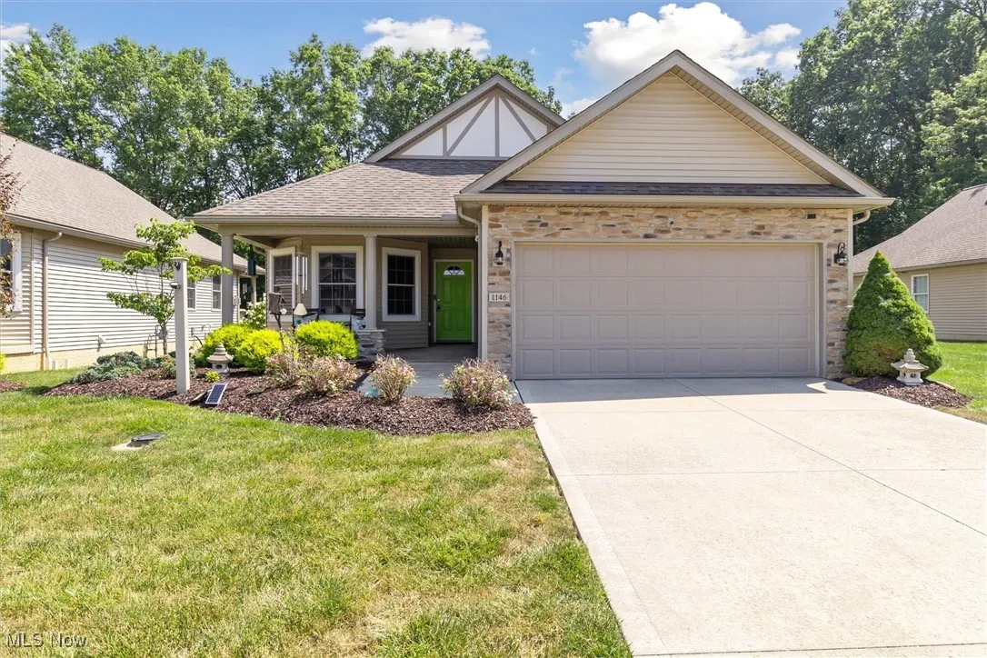 View of front of property featuring a front yard, driveway, a garage, and roof with shingles
