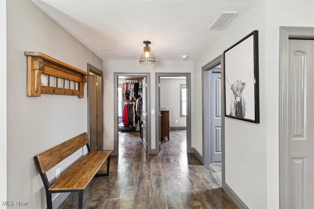 Corridor featuring dark wood-style floors and a textured ceiling